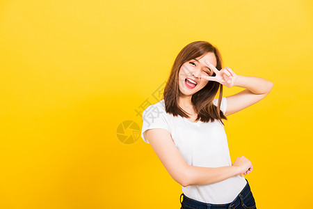 女青少年微笑站着穿着T恤的笑脸 展示手指制作自拍眼睛微笑手势工作室头发女孩胜利牙齿快乐图片
