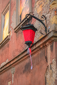 波兰卢布林一栋房屋的古城墙上挂着红色画布的旧街灯图片