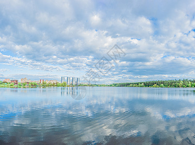 大蓝湖和天空 云彩美丽 海岸上有绿林 房屋和摩天大楼 风景全景图片