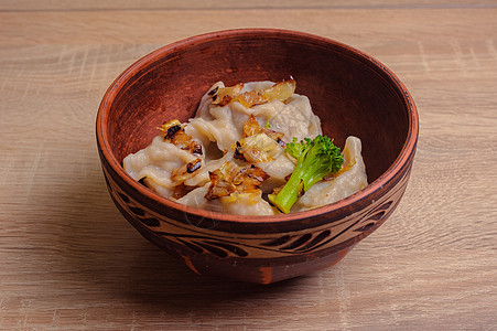 面团(皮罗吉 瓦列尼基) 洋葱油炸和花椰菜加装饰的棕色粘土板图片