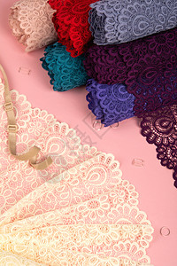 粉红色背景的带塑料配件的内裤和胸罩的精致鞋带卷 弹性材料 用于工作室和面料店新娘魅力裁缝蕾丝织物店铺裙子丝绸丝带磁带图片