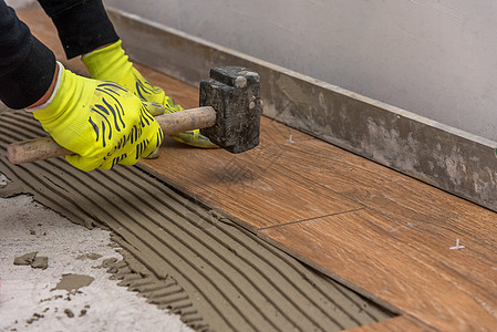 工人把陶瓷地板砖放在粘合表面大理石安装瓦工建筑砂浆职业工具推杆石匠地板图片