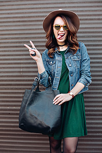 时髦的黑发 在太阳镜和帽子上 假扮在街上项圈微笑衣服女士裙子销售牛仔裤城市女性冒充图片