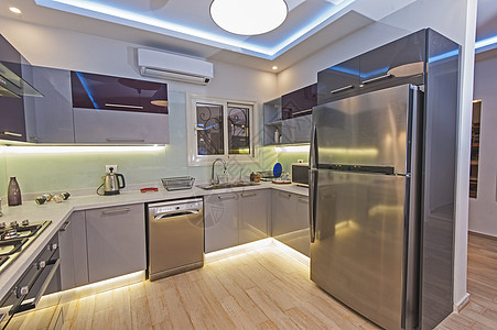 在豪华公寓的现代厨房台面洗碗机大理石窗户地面冰箱龙头家具设计木地板图片