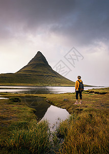 带着背包的年轻远足者望着冰岛Kirkjufell山冒险风景地标男性男生游客爬坡旅行火山半岛图片