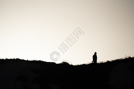 日落时在山上行走的人们的轮廓图片