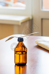紧靠窗口的勺子鸡尾杯瓶支气管炎窗户药物制药流感药品桌子糖浆茶匙药剂图片