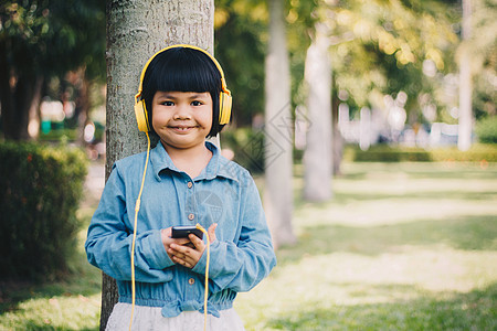 儿童概念和技术     带着耳机听音乐的笑笑女孩童年快乐孩子音乐头发手机家庭学校女孩横幅图片
