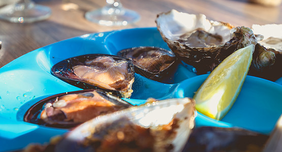 煮熟的牡蛎和贝贝 生在临近的桌边贝类生活生蚝熟食饮食柠檬石头食物美食盘子图片