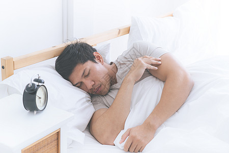 亚洲男人睡在白床上 带着闹钟的亚洲男人图片