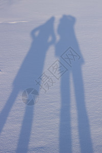 手握手在雪中创造阴影喜悦爱心海滩影子人蓝色夫妻乐趣摄影太阳旅行图片