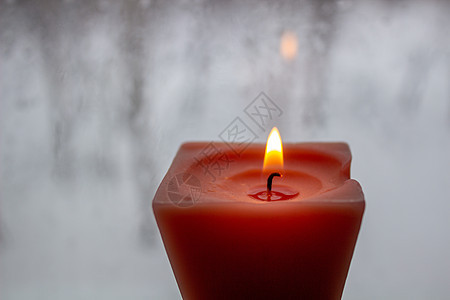 冬天晚上 烛光在寒冷的窗口附近燃烧着蜡烛下雨温暖烧伤毛线季节风格茶色房子框架玻璃图片