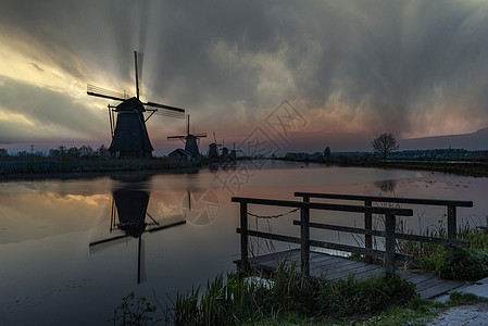 在荷兰运河中间的Unesco传统风力车轮椅上 亮光日出环境活力天空风车农村文化中心涡轮日落技术图片