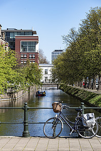 荷兰休闲自行车停在一座小桥的围栏上 在平静的运河上 在无云的天空下穿过海牙市的道路图片