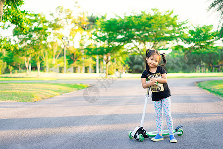 可爱的亚洲小女孩 在公园里学骑摩托车孩子滚筒童年幼儿园女孩街道木板学习乐趣喜悦图片