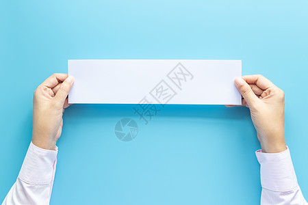 紧握空空空白水平纸的双手 供传单或请柬在蓝色背景上进行孤立模拟时使用文书商务商业卡片小样邀请函阅读文件夹手指工作图片