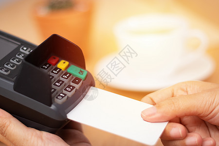 信用卡支付概念 在咖啡店的销售点终端用带有刷卡机的白色空白卡模拟近手插入信用卡背景图片