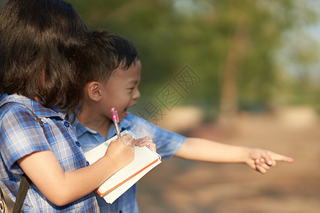 女孩和男孩在自然田间为书中的笔记一起聊天t图片