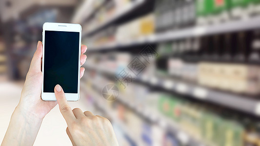 妇女在超级超市购物时使用智能电话的妇女手机店铺杂货店衣服贸易零售活动女性顾客购物者图片