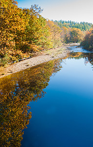 星期天的河水融汇着金色落叶彩色树叶的反射图片