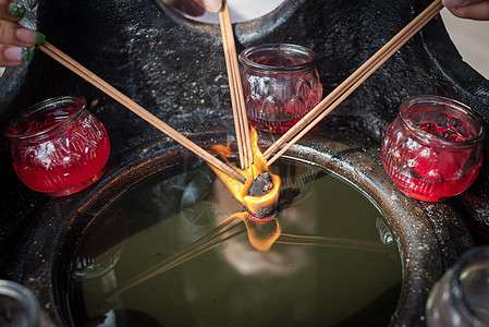 三只手握着香棍 在燃烧的蜡烛上图片