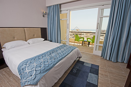 旅馆套间卧室家具小地毯羽绒被房间阳台玻璃门酒店海景椅子奢华图片