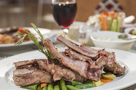 以标板板为牌盘的羊排肉食宏观白色红色点菜桌子餐厅玻璃盘子羊肉图片