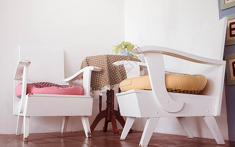 白色木制椅子和漂亮的彩色桌子的木制桌后院枕头阳光闲暇扶手椅植物座位奢华花园风格图片