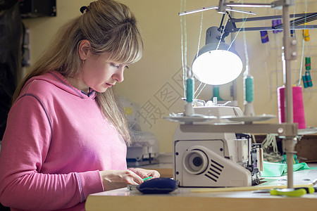 女孩用缝纫机在柜台做针线工作图片