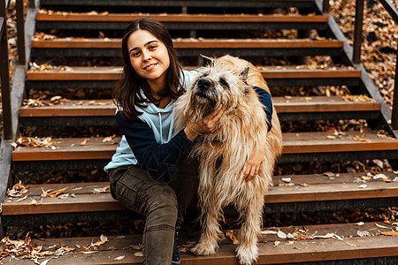 动物训练 一名志愿者女孩从动物收容所带着一只狗散步 在秋天的公园里带着狗的女孩 和狗一起散步 照顾动物猎犬犬类成人女士乐趣小狗运图片