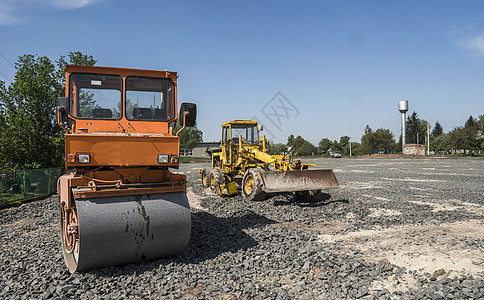 在道路建设和修复沥青路面时 用蓝色的天空在石块上架立着橙色光振动滚压机工程建筑振动街道压实机活动机器赛跑者柏油卡车图片