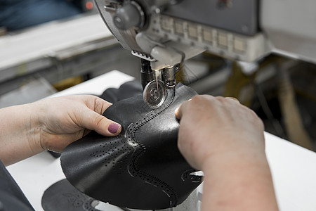 皮革车间的缝纫机在用手处理鞋子的皮革细节 在鞋厂 老妇人的手拿着缝纫机工人工具制造业商业金属奶牛家具生产工艺机械图片