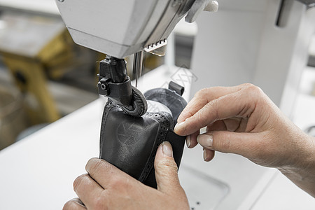 皮革车间的缝纫机在用手处理鞋子的皮革细节 在鞋厂 老妇人的手拿着缝纫机接缝工作行动材料衣服纺织品商业机械缝纫裁缝图片