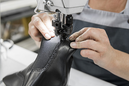 皮革车间的缝纫机在用手处理鞋子的皮革细节 在鞋厂 老妇人的手拿着缝纫机制造业缝纫工人工厂水牛工作奶牛生产工艺裁缝图片