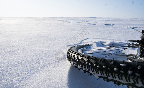 山地自行车躺在冬季田野的白雪上 背景是蓝天空雾凇梗阻季节天气车辆气候三角困苦框架阻碍图片