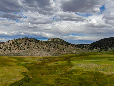 Aspen泉以山为背景的绿地和小曲线河流的空中观测图景山脉地标反射国家远足池塘风景场地天空山坡图片
