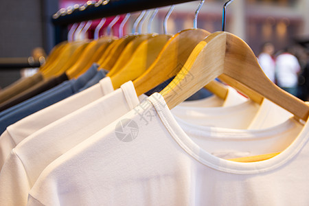 挂在衣架上的多彩色T恤 在百货商店出售架子织物衬衫收藏壁橱服装衣服店铺裙子男人背景图片