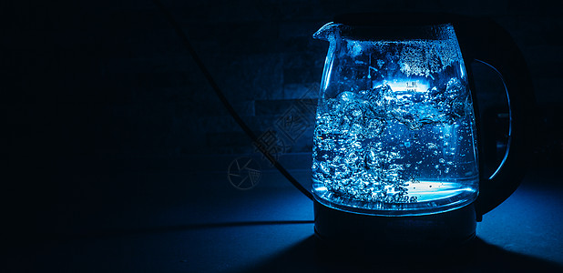 黑色背景上带蓝色背光的沸腾玻璃黑茶壶温泉蒸汽饮料水滴厨房气泡海浪液体蓝光厨具图片