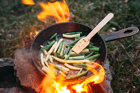 在锅里串豆子 在大火中煮蔬菜早餐森林食物煎锅乡村美食煤炭旅行平底锅野餐图片