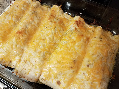 炉子上玻璃锅里有奶酪的enchiladas平底锅食物火炉午餐图片