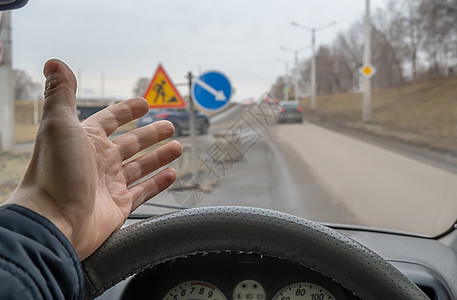 汽车车轮后一位司机的手掌掌 他因道路修理和安装路标而感到愤怒图片