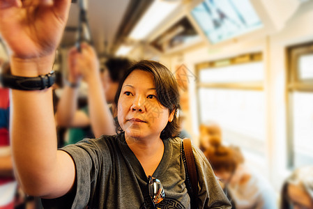 亚裔女性在城市上乘天际火车旅行天空小时轻轨游客过境铁路商业旅游首都民众图片