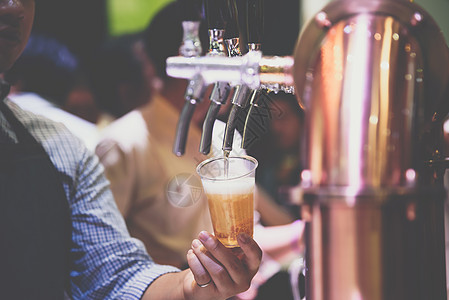 酒吧老板或酒保在啤酒龙头倒啤酒酿造服务调酒师服务员啤酒厂草稿液体派对泡沫命令图片