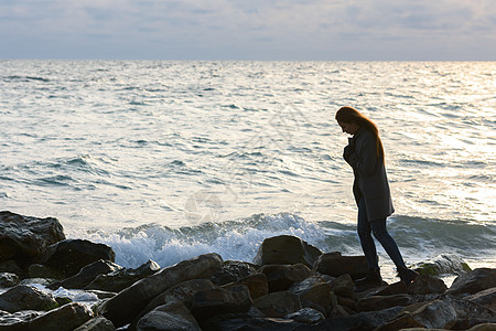 寂寞的姑娘在沉闷的心情中 在岩石海岸上走来走去图片