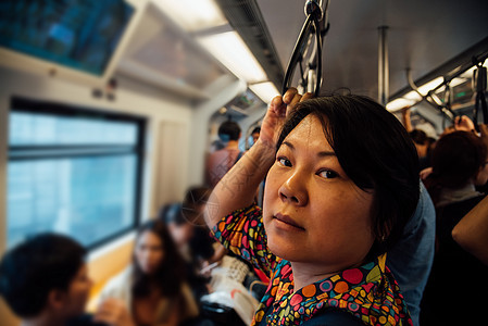 亚裔女性在城市上乘天际火车旅行平台民众技术首都乘客女士铁路人群天空地铁图片
