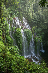 巴厘岛山区高处美丽的瀑布 玻璃上和之间许多溪流的水流长着茂密的热带植被 印度尼西亚风景旅游旅行地标岩石流动植物假期树木荒野图片