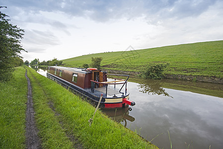 英国运河上的窄船在农村的一条小河上人行道自行车爬坡假期船尾天空水路纤道舵柄反射图片