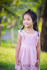 可爱小女孩的肖像 在公园里站着女孩童年粉色微笑裙子绿色花园儿童孩子快乐图片