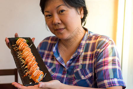 亚裔女性在饭盘上握着加州卷卷寿司喜悦食品饮食头发女士自助餐美丽橙子女孩图片