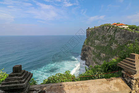 印度尼西亚巴厘岛的乌鲁瓦图悬崖与凉亭和蓝色大海的景色 寺的美丽风景 白天有五颜六色的鲜花前景 高悬崖风景秀丽的沿海景观日落吸引力图片